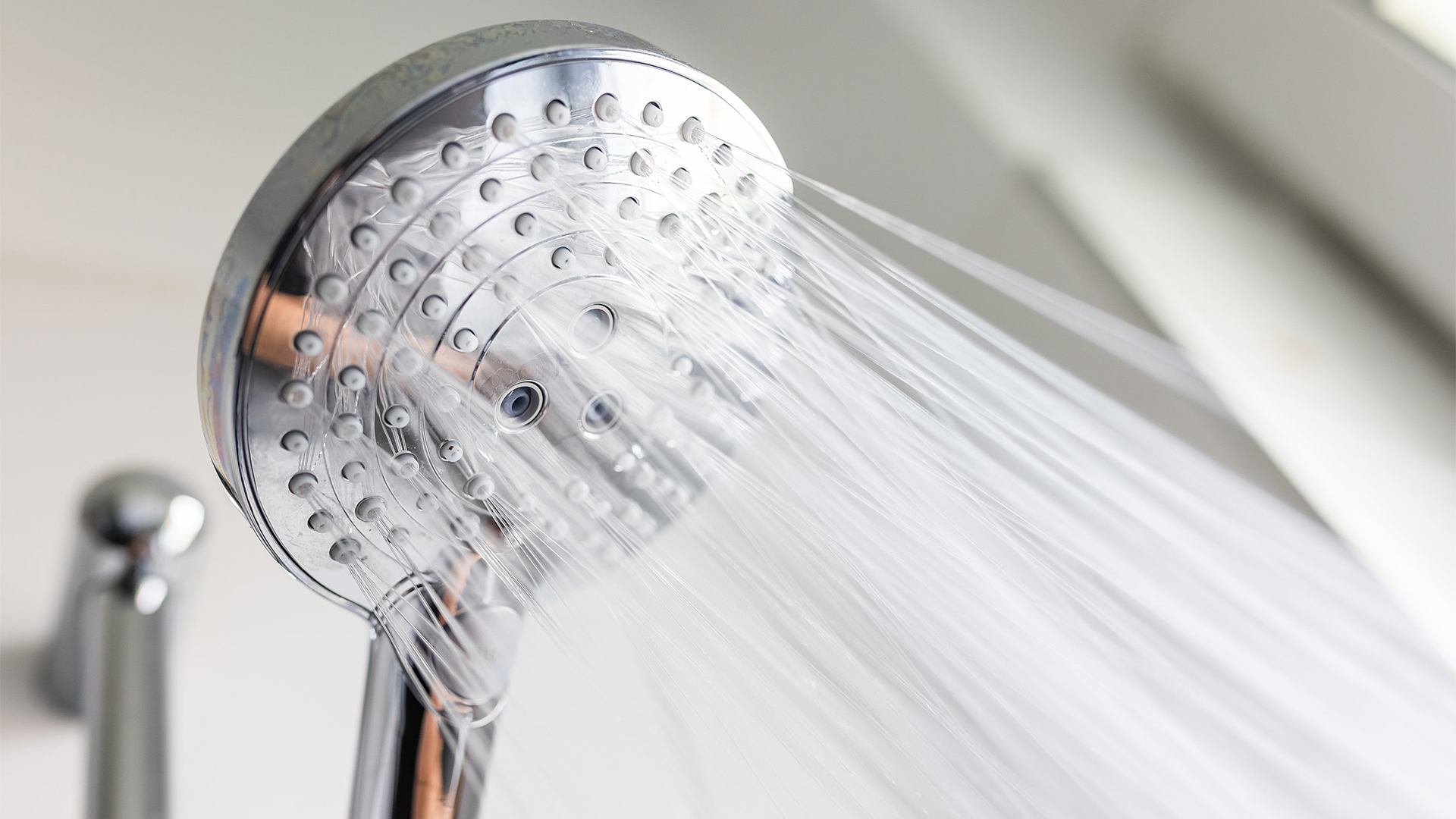 Aus einem Duschkopf spritzen viele dünne Wasserstrahlen.
