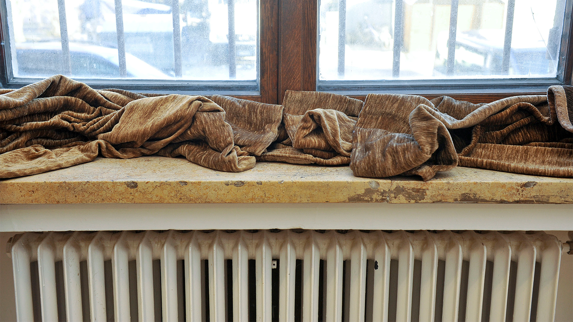 Eine Decke liegt auf der Fensterbank über einem Heizkörper in einem Altbau.
